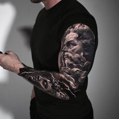 a man with tattoos on his arm holding a cell phone