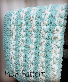 a blue and white crocheted blanket sitting on top of a table