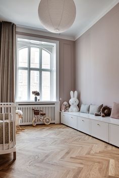 a baby's room with wooden floors and white furniture