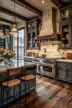 a large kitchen with wooden floors and gray cabinets, an island countertop and two pendant lights hanging from the ceiling