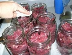 several jars filled with red meat sitting on top of a stove