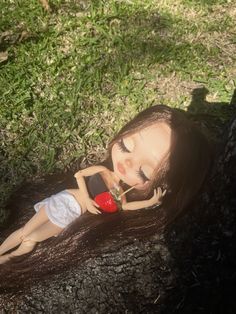 a doll is laying on the ground with her head resting on a red object in her hand