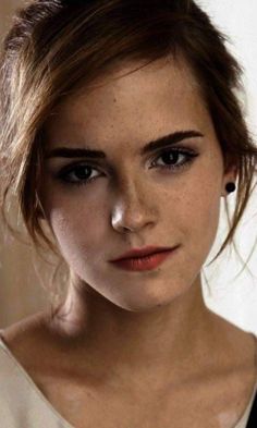 a close up of a person wearing a white shirt and brown hair with freckles on her head