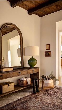 a living room with a large mirror on the wall next to a table and lamp