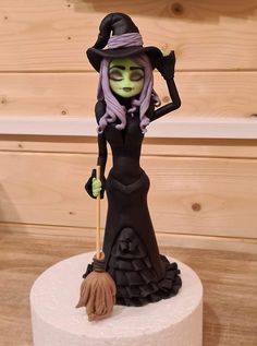 there is a cake that looks like a witch on top of the cake and has a broom in her hand