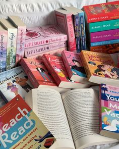 a pile of children's books sitting on top of a white bed spread out