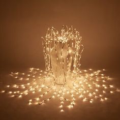 a lighted vase sitting on top of a white floor next to a light bulb covered box