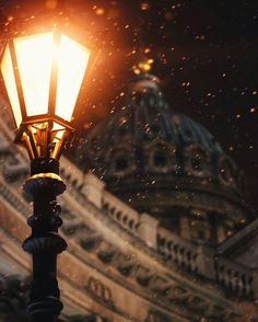 an old fashioned street light in front of a building at night with snow falling on the ground