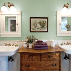 two sinks in a bathroom with green walls and white trim on the wall above them