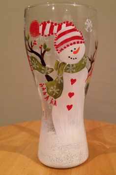 a frosty glass with a snowman holding a heart on it's side