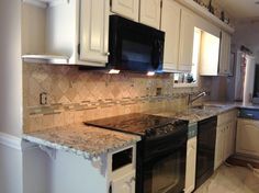 a kitchen with white cabinets and black appliances