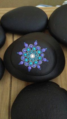 some black rocks with blue and purple designs on them are sitting on a wooden surface