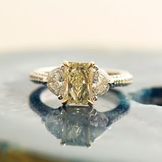 a fancy yellow diamond ring sitting on top of a table