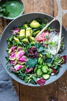 a salad with spinach, cucumbers and parmesan cheese in a bowl