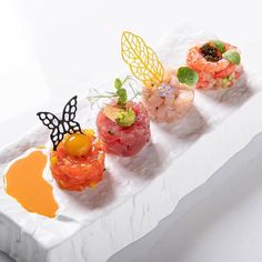 three small sushi dishes on a white tray