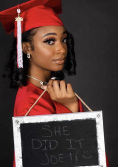 a woman wearing a graduation cap and gown holding a sign