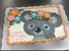 a birthday cake decorated with a koala bear and flowers