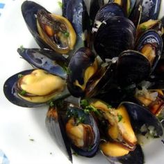 a plate full of steamed mussels on a table