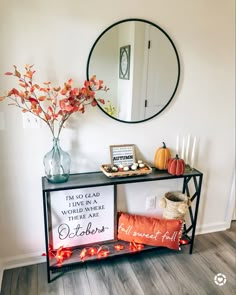 a table with a mirror and some candles on it next to a vase filled with flowers