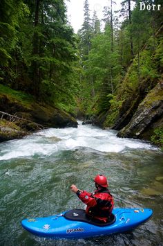 a man riding on top of a blue kayak in the middle of a river