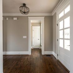 an empty room with hard wood floors and white trim on the doors, windows, and door knobs