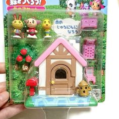 a person holding up a toy house with animals in the front and on the back