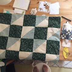 someone is making a quilt on the floor next to their crafting tools and supplies