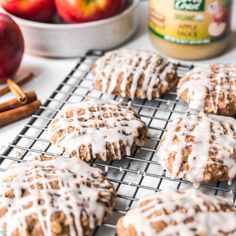 apples and cinnamon donuts on a cooling rack next to an apple in the background