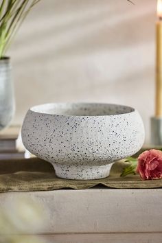 a white bowl sitting on top of a table next to a candle and some flowers