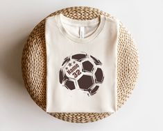 a t - shirt with a soccer ball on it sitting on a wicker basket