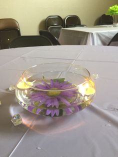 a glass bowl filled with flowers on top of a white table cloth covered dining room table