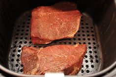 two steaks are cooking in an air fryer