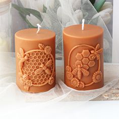 two bees and honeycombs carved candles on a lace tablecloth with flowers in the background