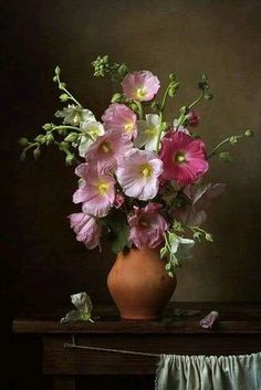 a vase filled with pink flowers sitting on top of a wooden table