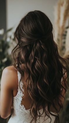 the back of a woman's head wearing a wedding dress and holding her hair in one hand