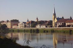 a river with buildings on both sides and a church steeple in the back ground