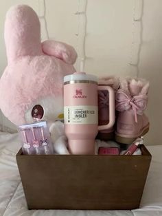 a pink teddy bear sitting on top of a bed next to a cup and other items