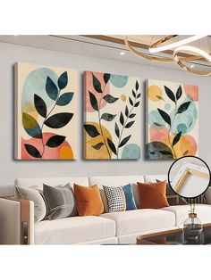 three paintings hanging on the wall above a white couch in a living room with a coffee table