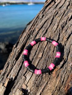 a pink and black bracelet sitting on top of a tree