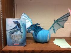 a blue dragon figurine sitting on top of a shelf next to two books