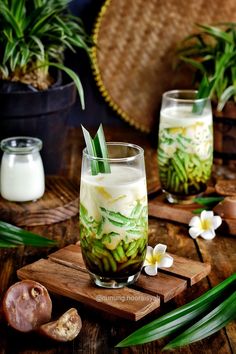 two glasses filled with food sitting on top of a wooden table next to some plants