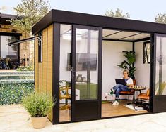 a person sitting at a table in front of a house with glass walls and doors