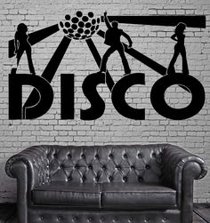 a couch sitting in front of a brick wall with the word disco on it and three people