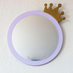 a mirror with a crown on it hanging on the wall next to a white wall