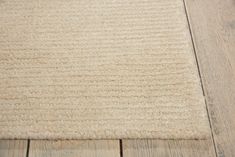 an area rug on the floor with wood floors in the background and a white wall