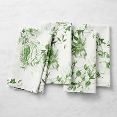 four white napkins with green flowers on them