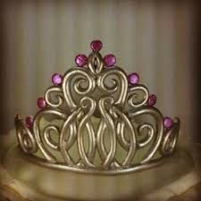 a silver tiara with pink stones on the top and bottom, sitting on a table