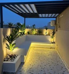 an outdoor area with plants and lights on the walls, along with concrete benches that are lit up at night