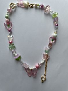 Embrace the whimsical charm of our Fairycore Butterfly Necklace! This handmade beaded necklace features a delightful mix of pink and green beads, adorned with butterflies, hearts, and flowers. Perfect for adding a touch of fairycore and kawaii style to any outfit, this necklace is a must-have for those who love unique and playful jewelry. Ideal for personal use or as a thoughtful gift, this necklace is designed to bring joy and enchantment to your accessory collection. The intricate beadwork and Whimsical Necklaces With Heart And Round Beads, Sweet Pink Jewelry With Colorful Beads, Pink Handmade Sweet Necklace, Handmade Pink Sweet Necklace, Handmade Sweet Pink Necklace, Pink Round Beads Kawaii Jewelry, Cute Beaded Charm Necklaces, Cute Pink Heart Beaded Necklaces, Cute Handmade Green Beaded Necklaces