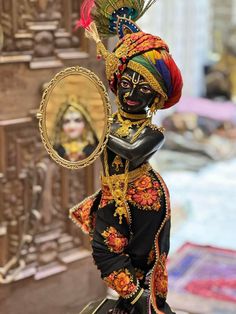 a woman in costume holding a mirror and looking at her face with an ornate headdress